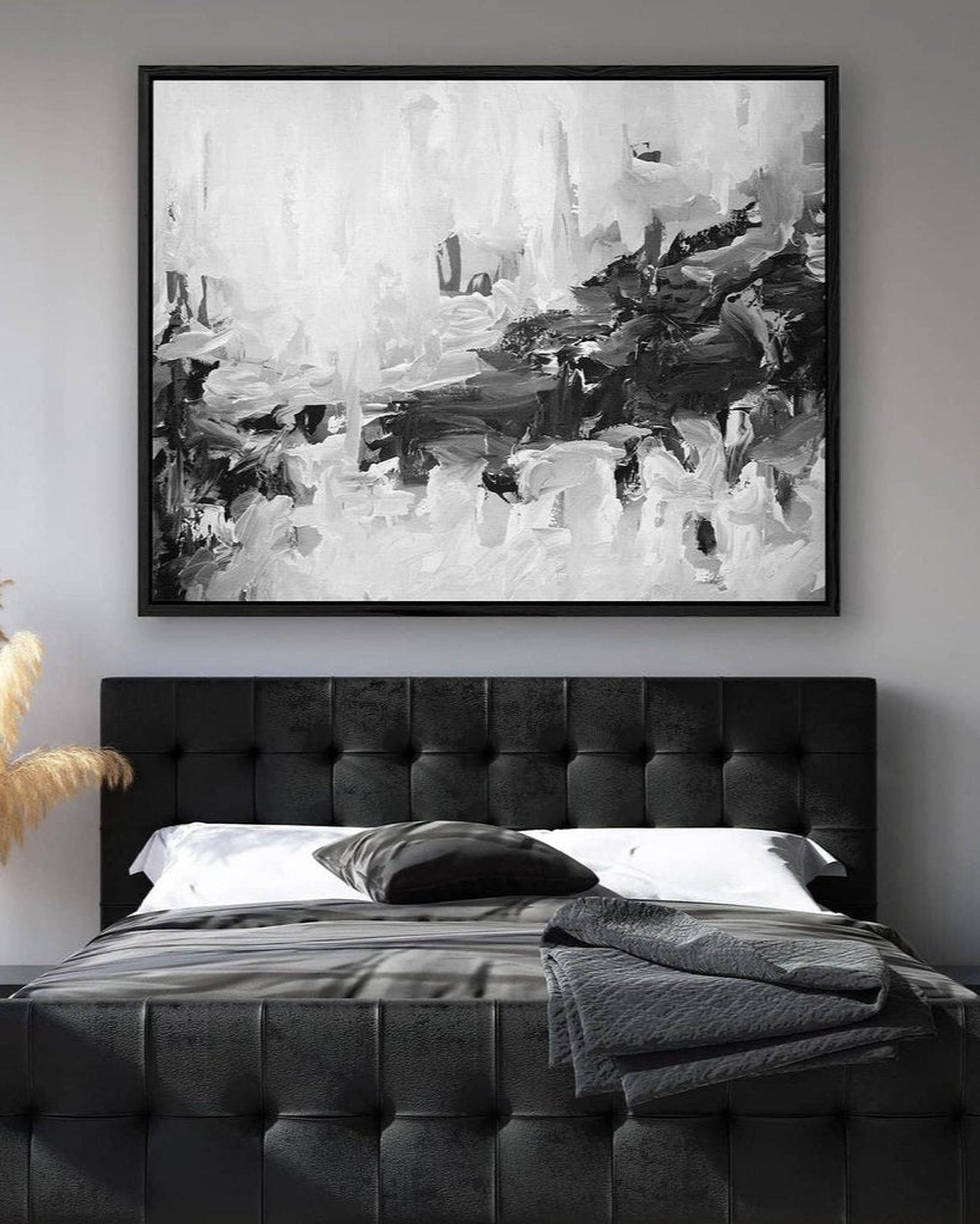 Abstract black and white painting above a bed with a tufted headboard.
