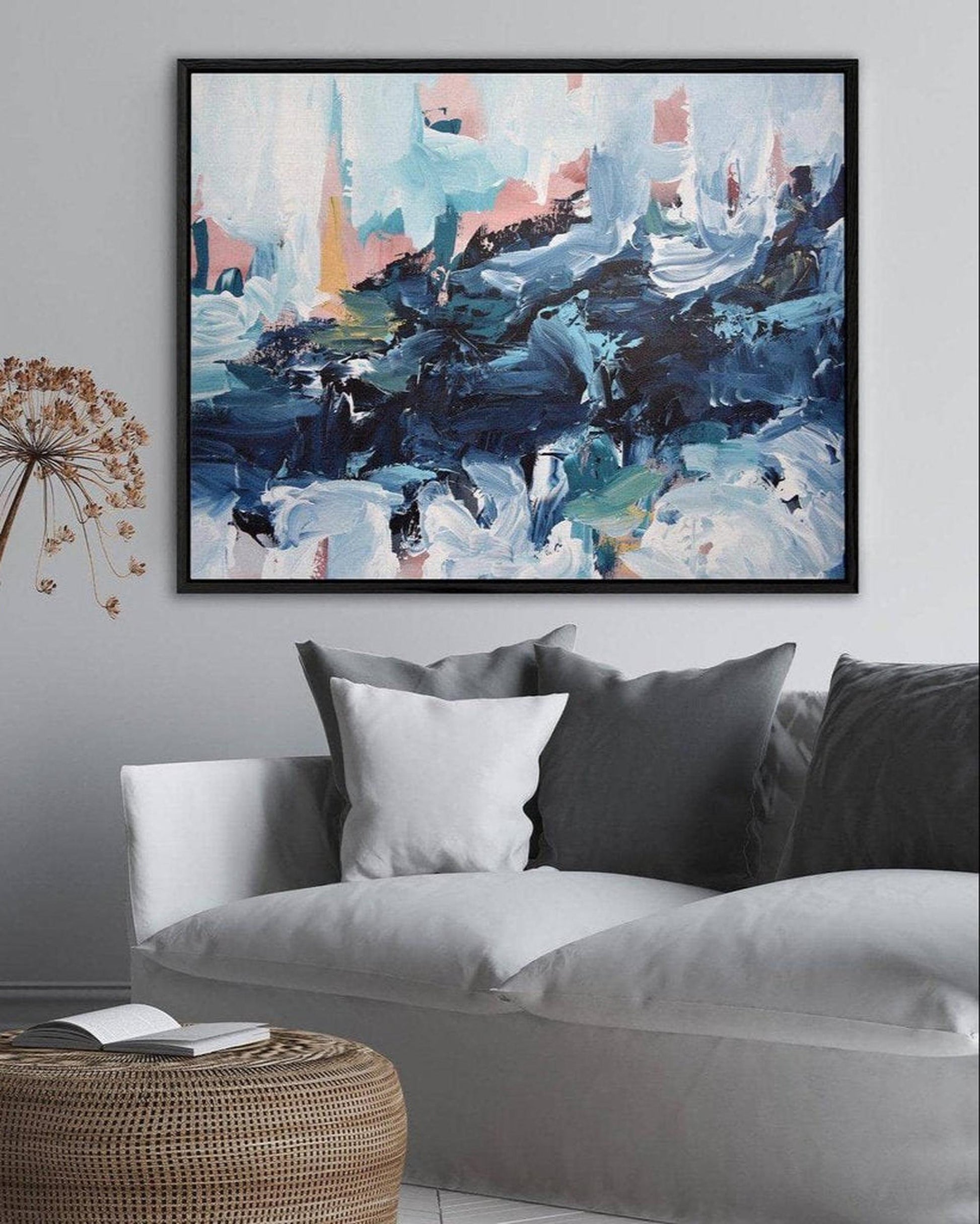 Abstract painting on a wall above a gray sofa with decorative pillows.