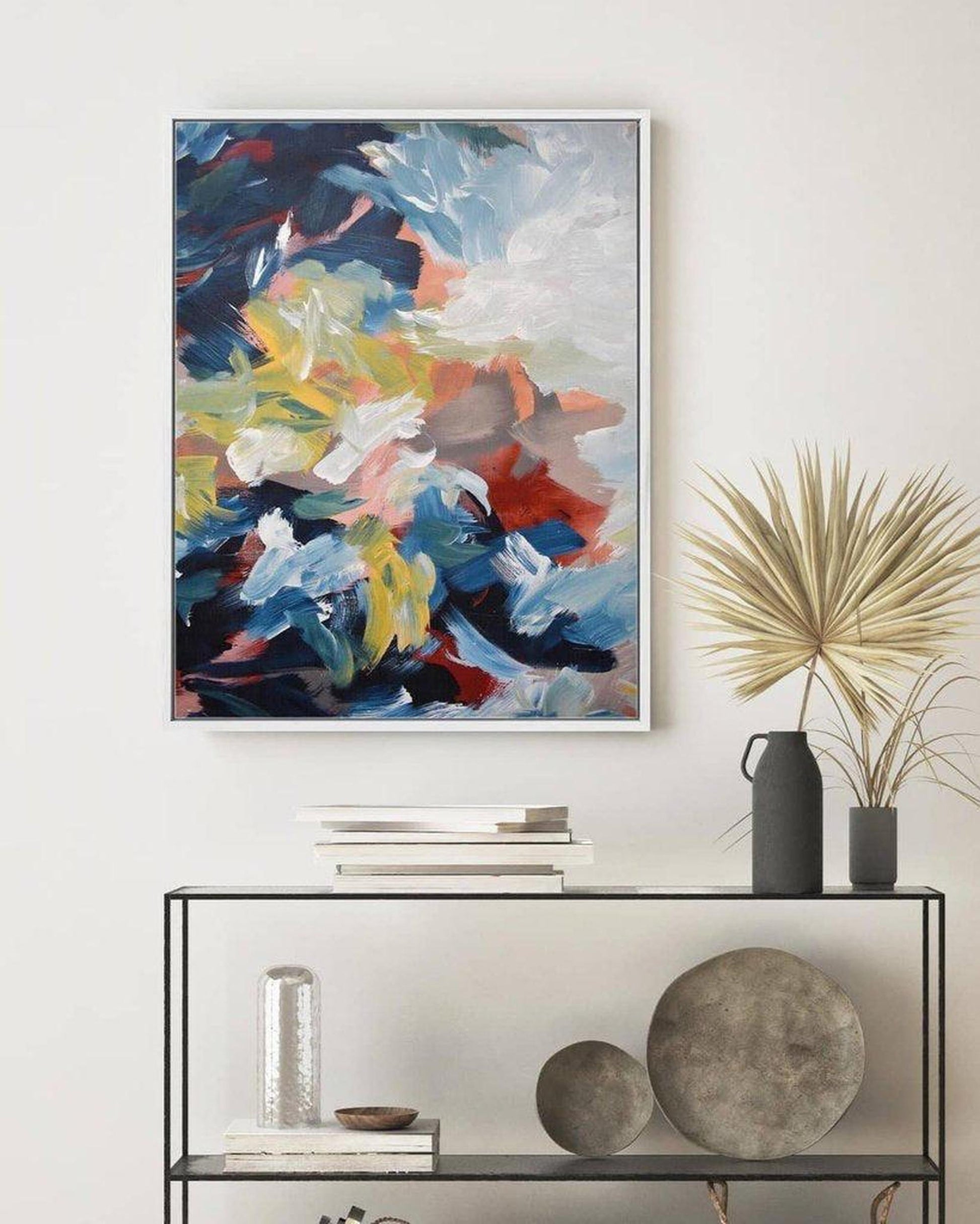 Abstract painting on a wall above a console table with decorative items.