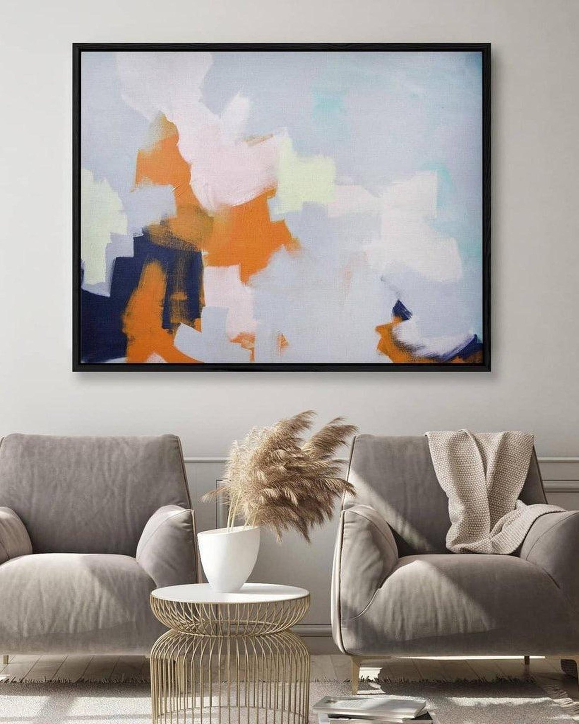Abstract art piece in a living room with gray chairs and a coffee table.