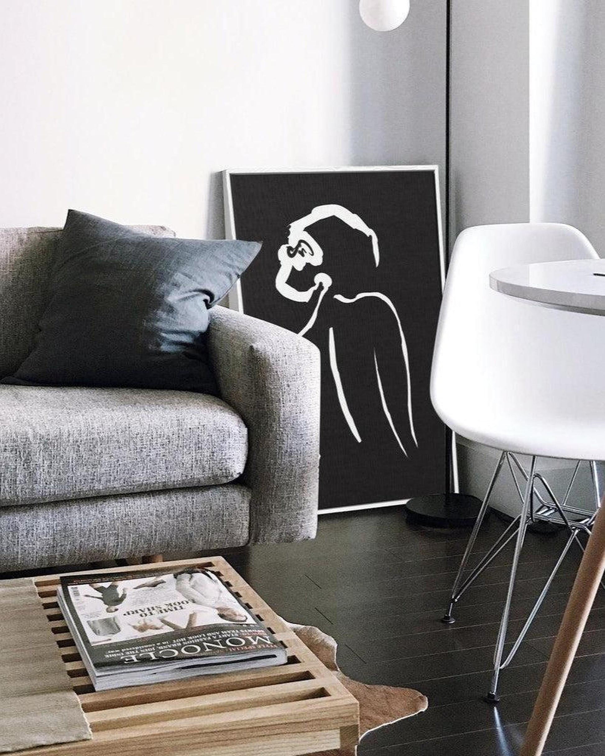 Modern living room with a gray sofa, wooden coffee table, and abstract art on the wall.