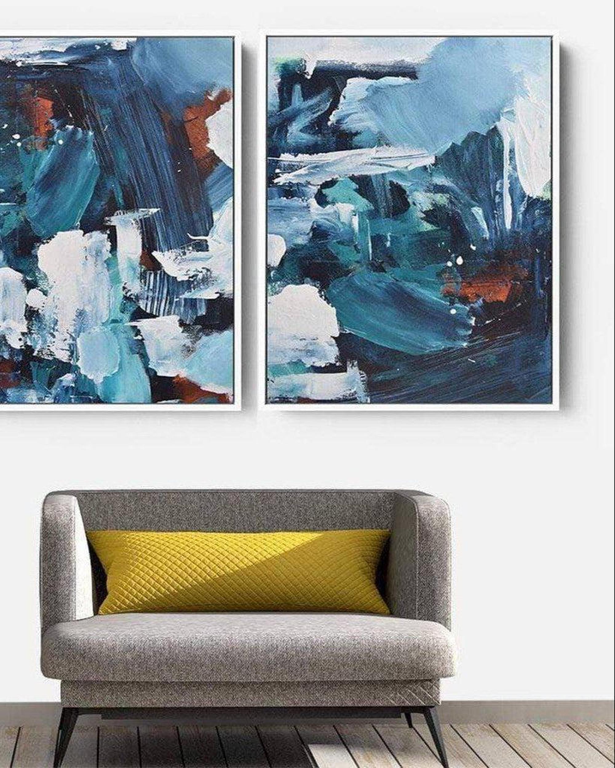 Two abstract paintings above a gray sofa with a yellow pillow.