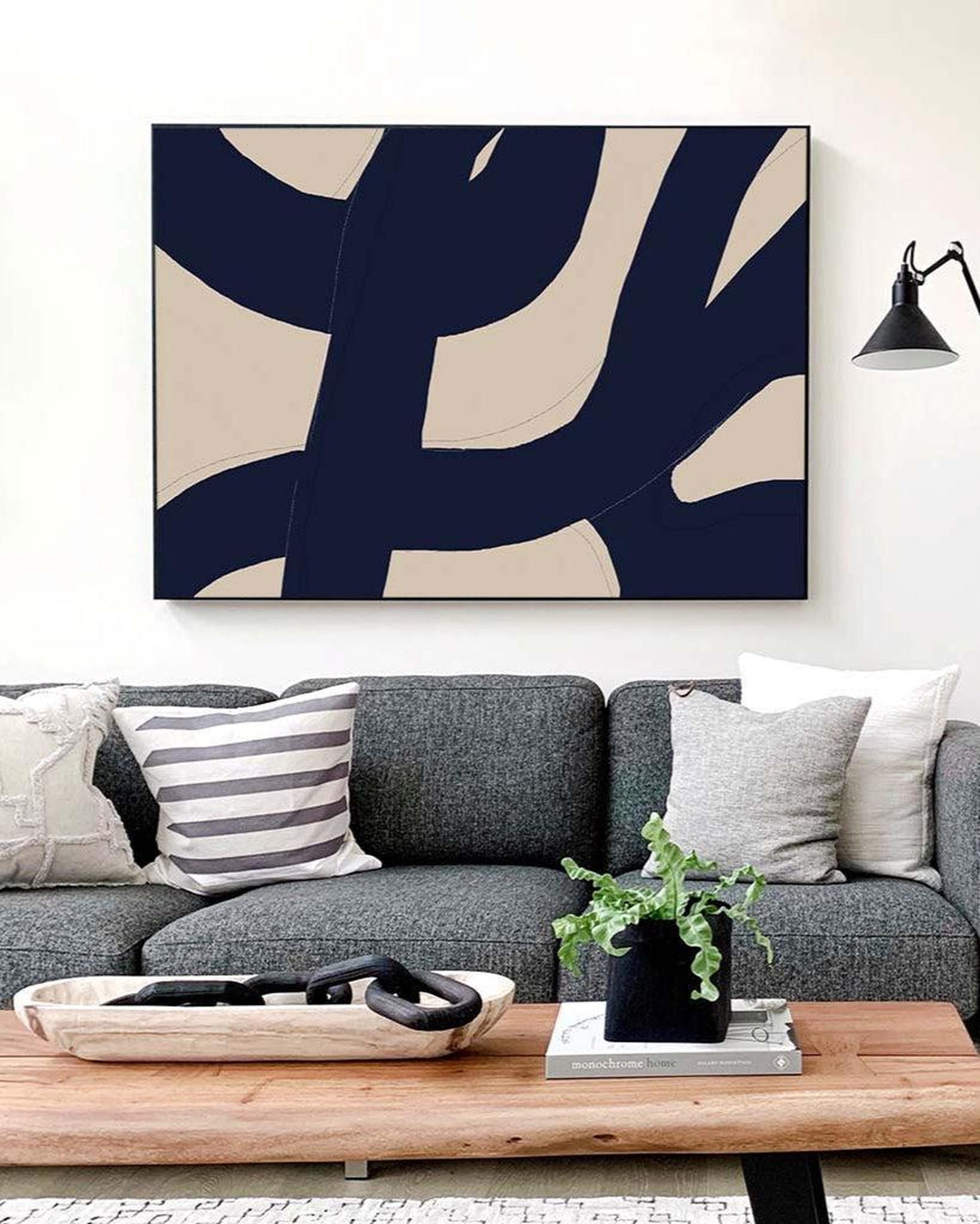 Living room with a gray sofa, abstract art on the wall, and a wooden coffee table.