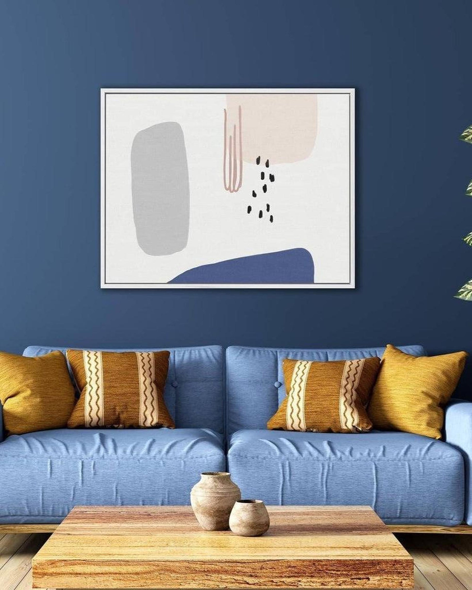 Blue sofa with yellow pillows against a blue wall with abstract art