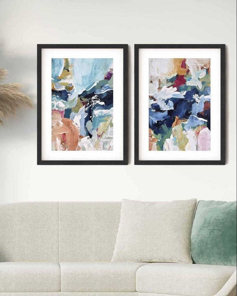 Two framed abstract art prints hanging on a wall above a white sofa, with one print slightly cut off by the right edge of the image.