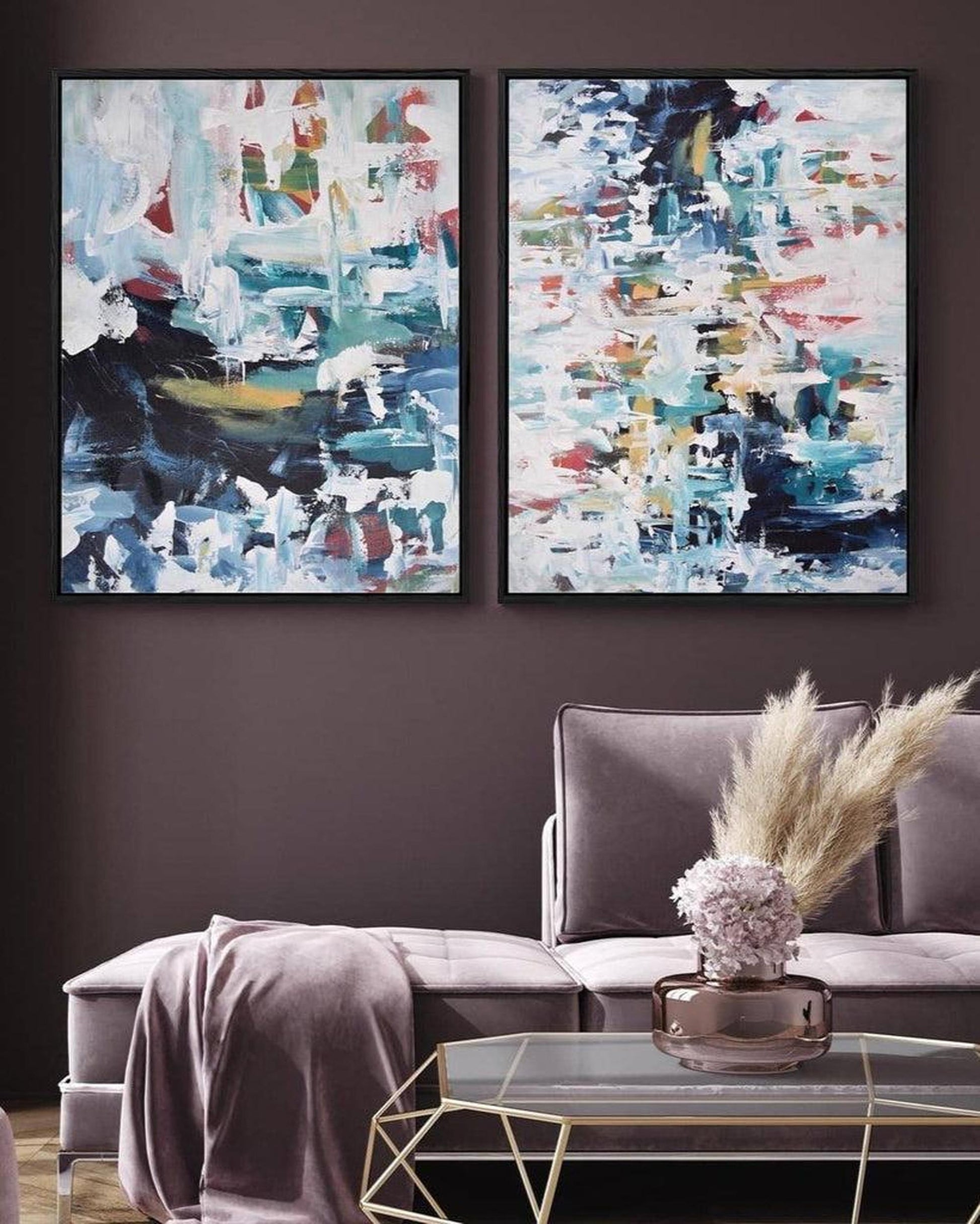 Two abstract paintings on a dark wall above a gray sofa.