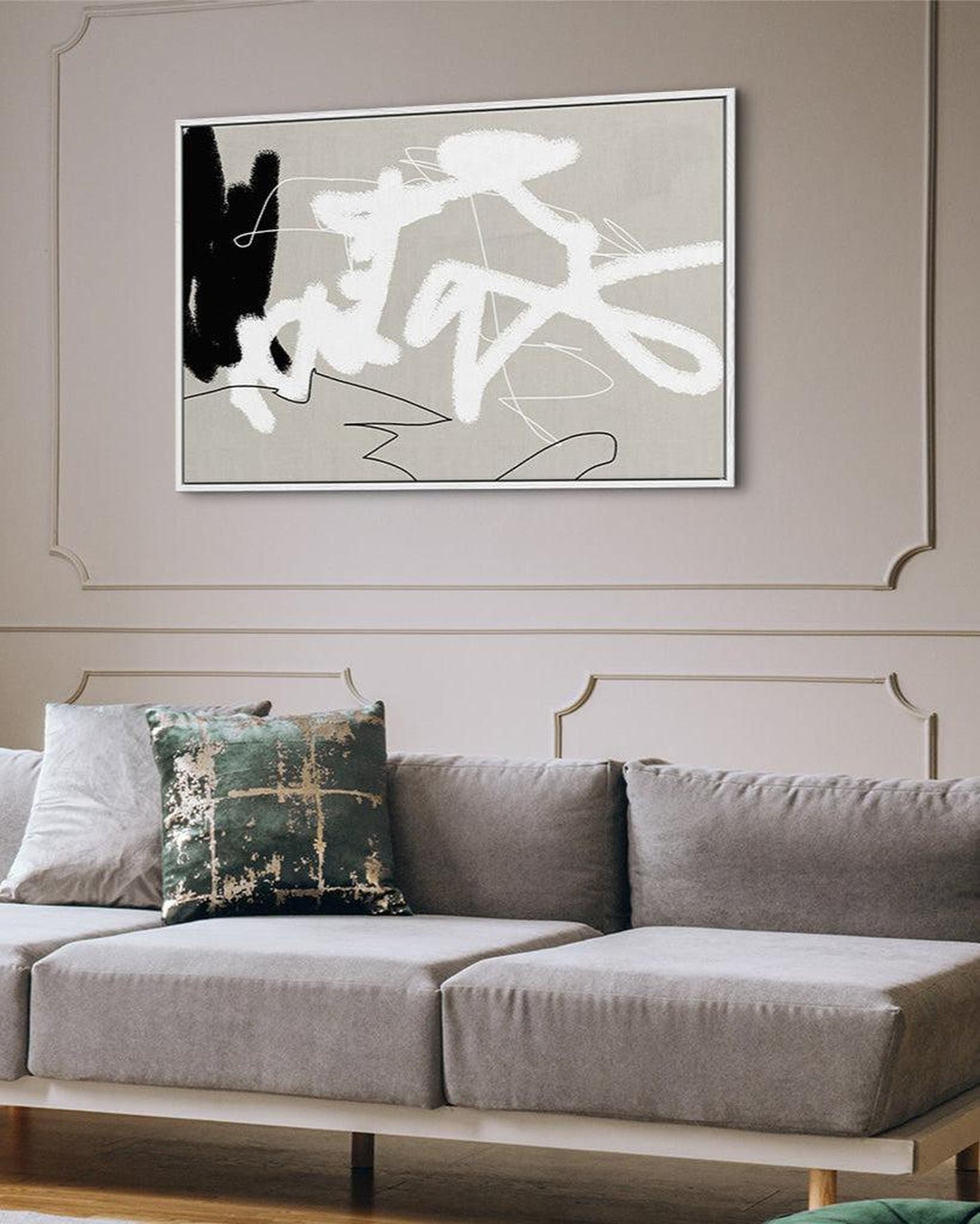 Gray sofa with a decorative pillow in a living room setting, featuring an abstract painting on the wall.