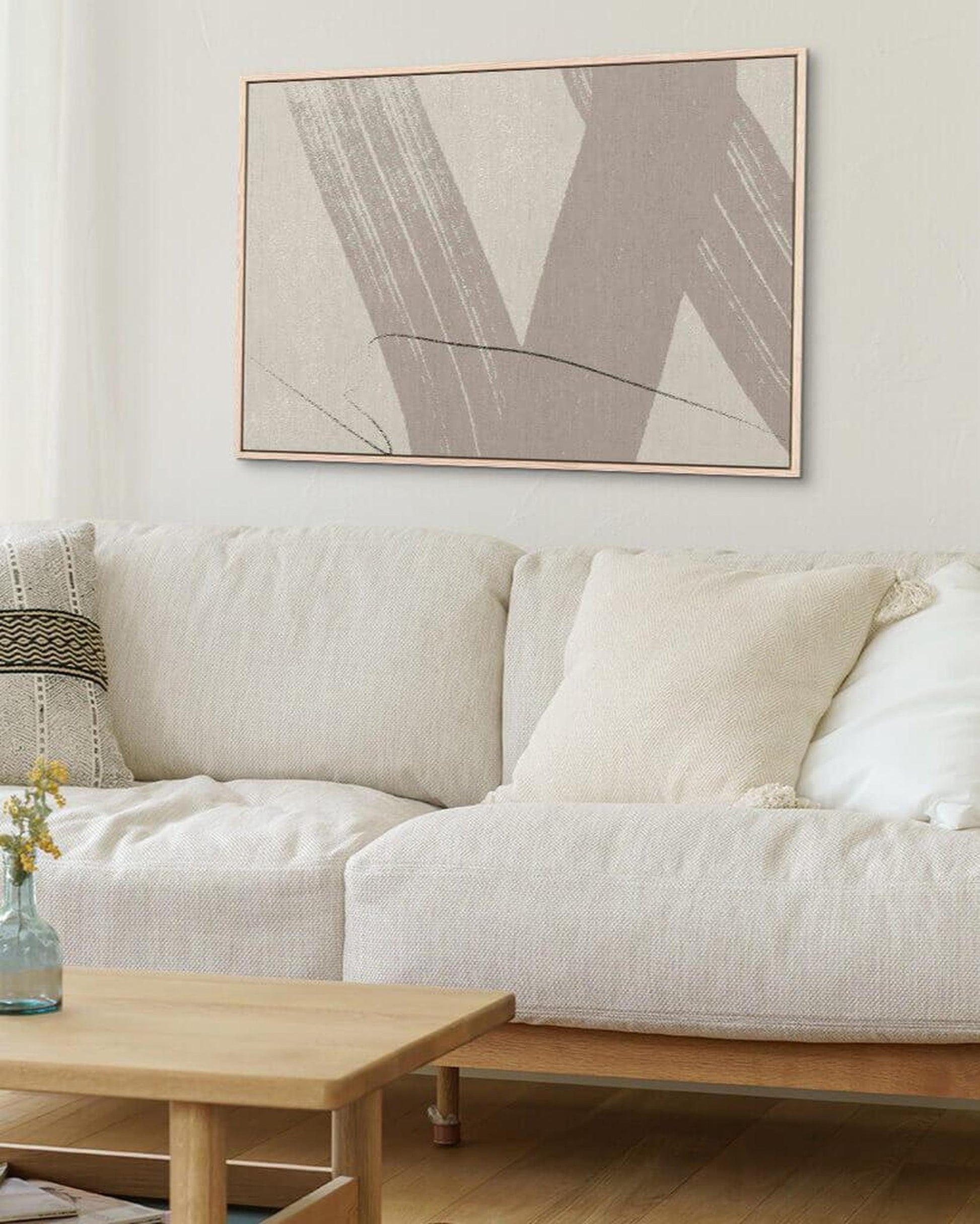 White sofa with a wooden coffee table and abstract art on the wall in a living room.