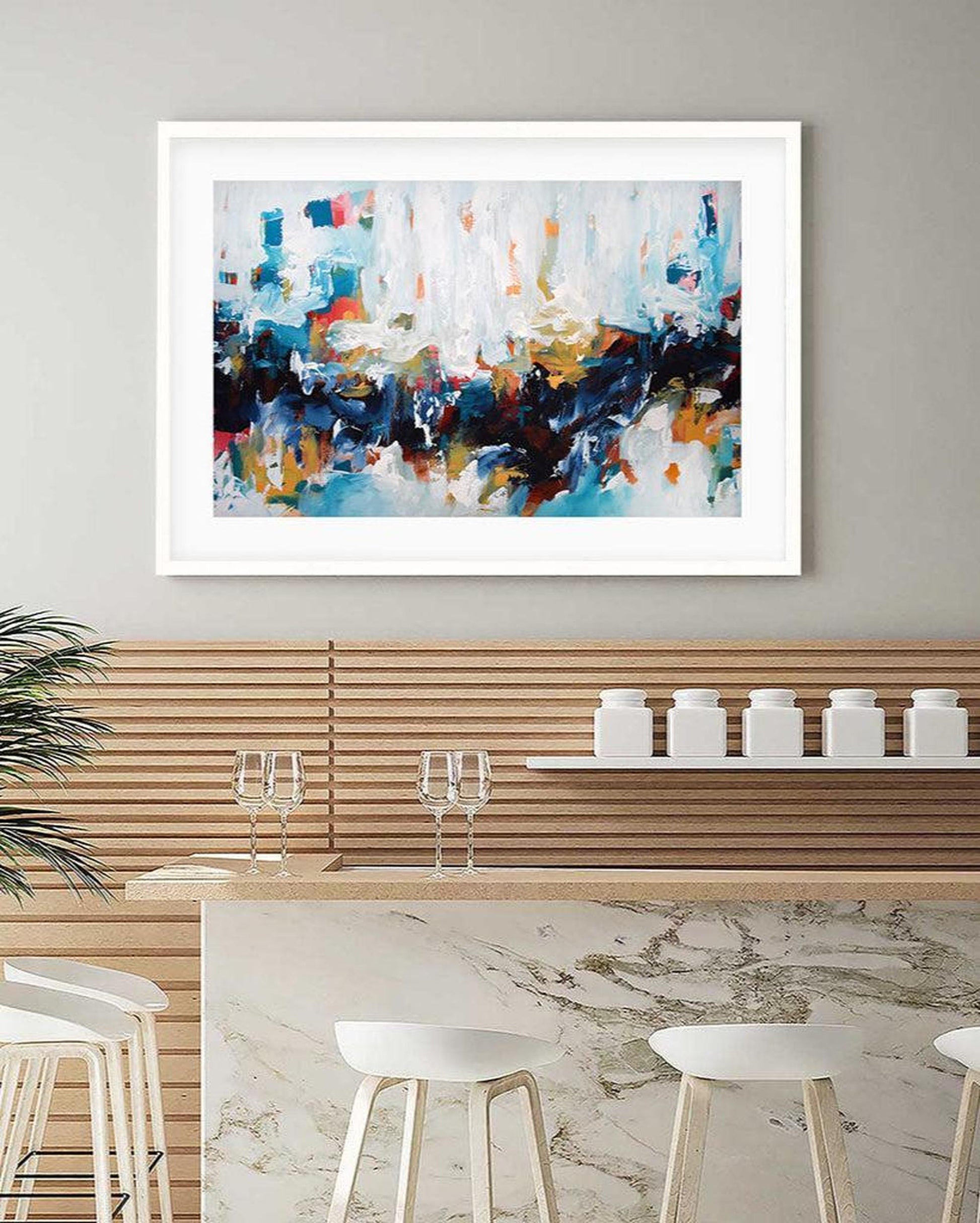 Abstract art painting in a modern kitchen setting with marble countertop and wooden cabinets.