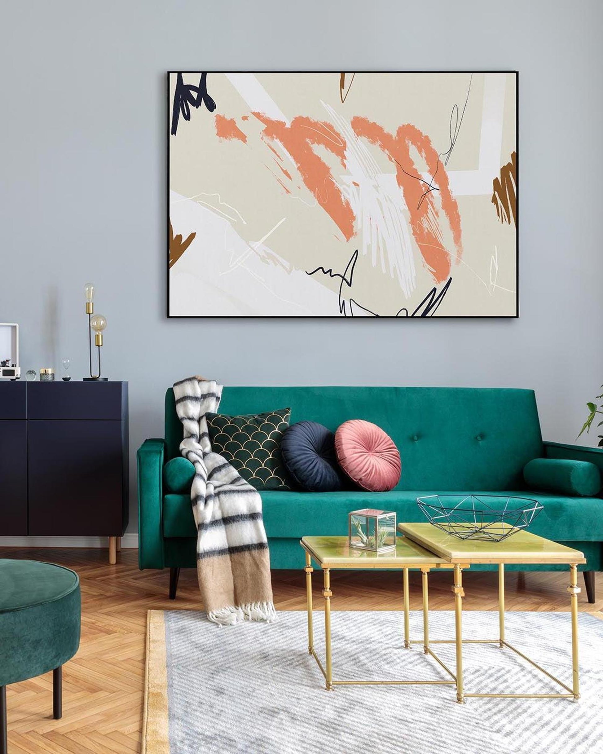 Modern living room with teal sofa, abstract art, and gold coffee table.