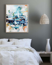 Abstract painting on a wall above a bed with a vase on a nightstand.