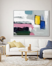 Modern living room with a white sofa, abstract painting, and decorative items.