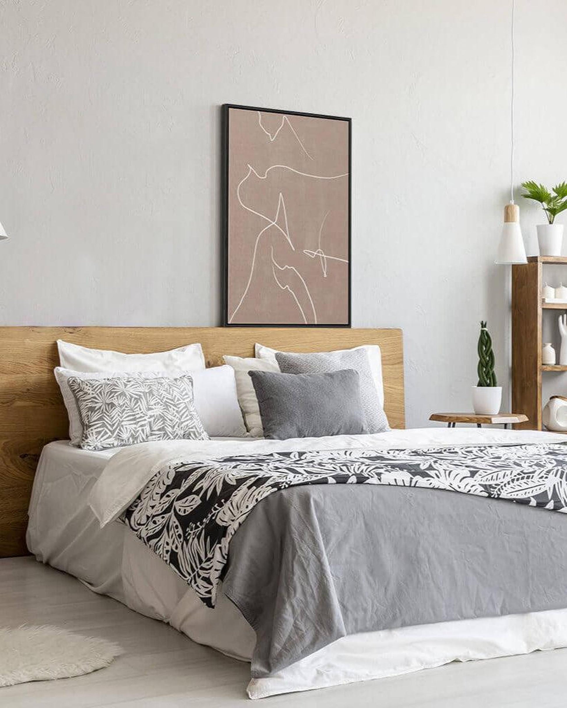 Neatly made bed with decorative pillows and a framed abstract art piece on the wall.