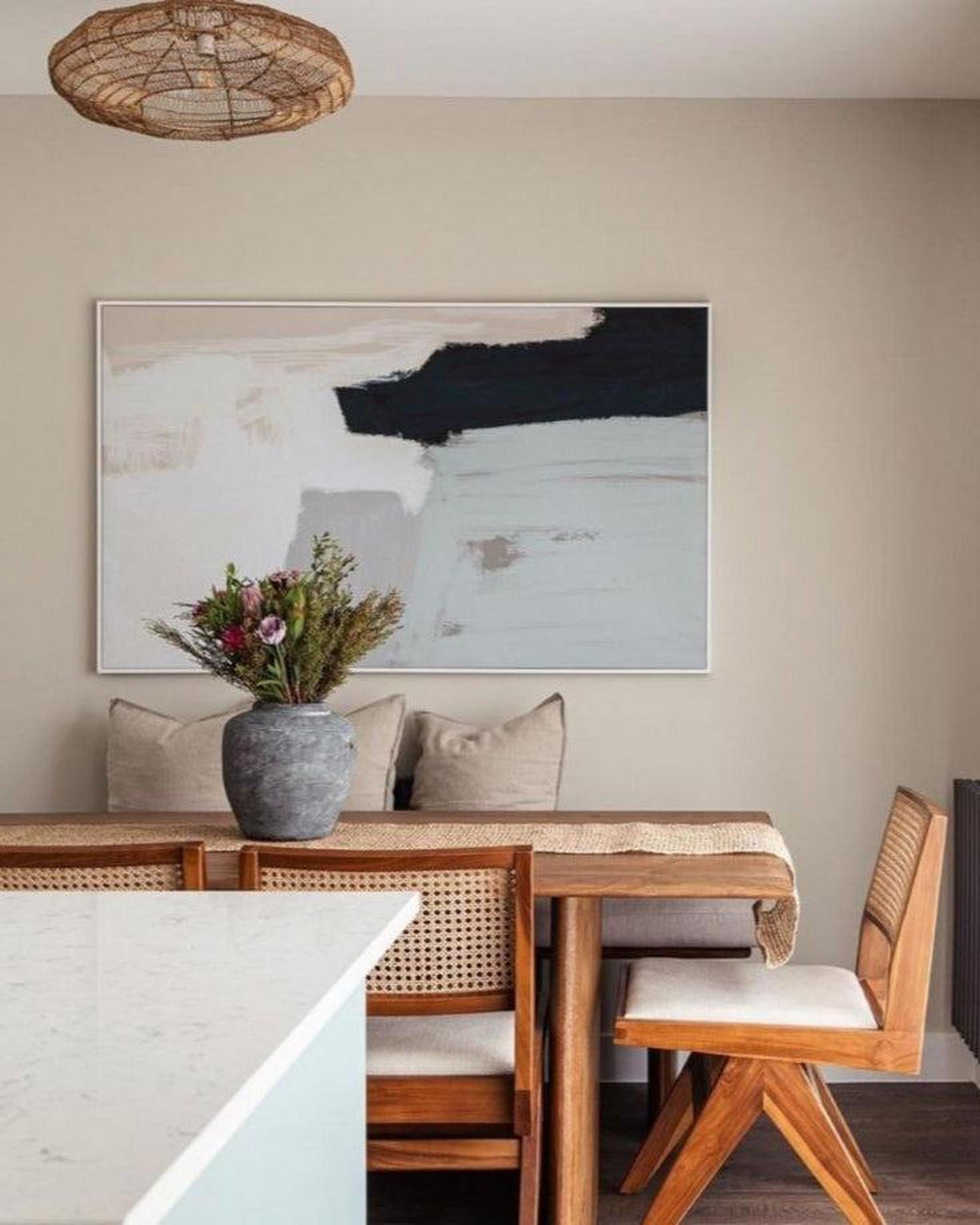 Dining room with wooden table, chairs, and abstract art on the wall.
