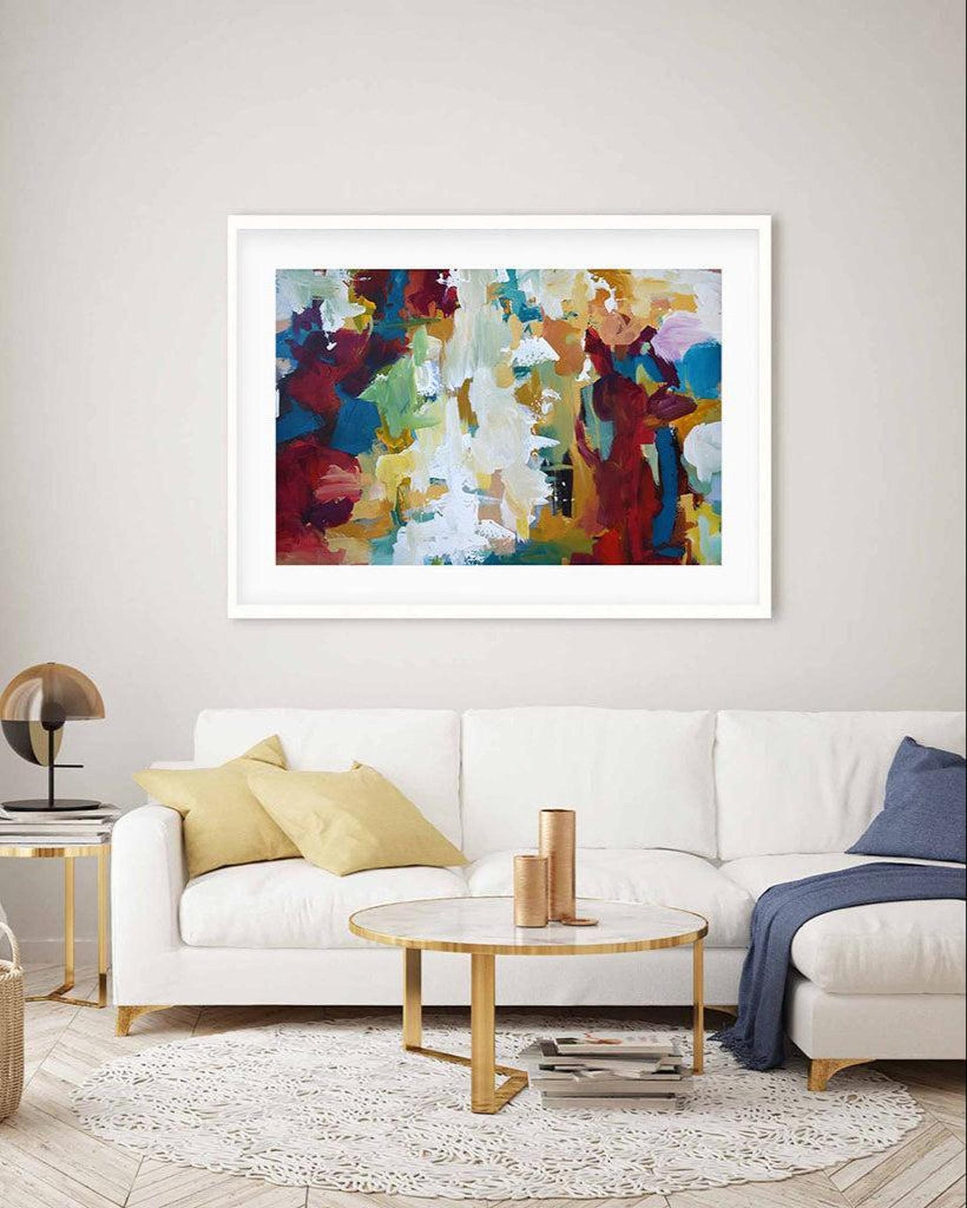 Colorful abstract painting on a wall above a white sofa in a living room.