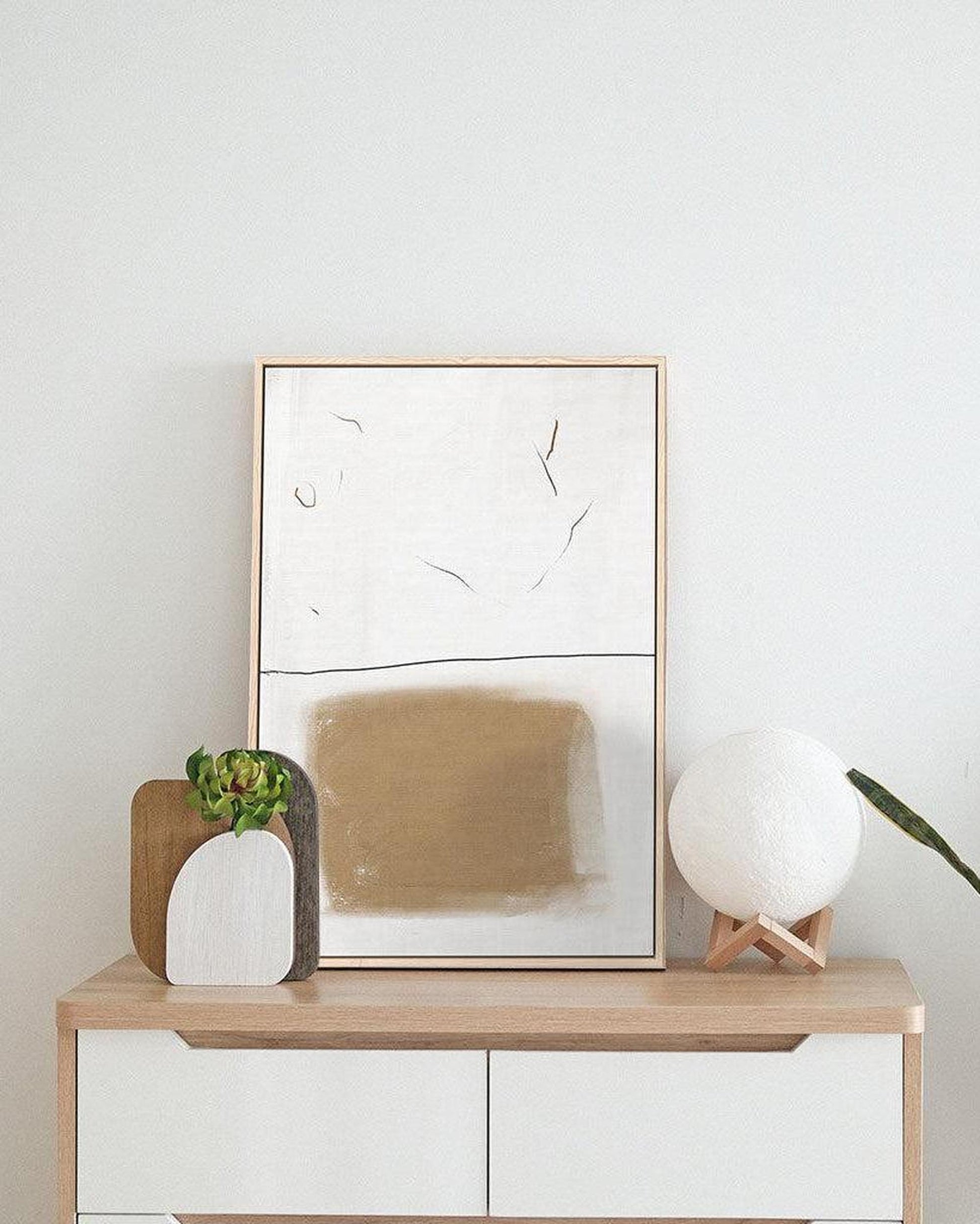 Modern interior with a wooden console table, abstract art, and decorative items.